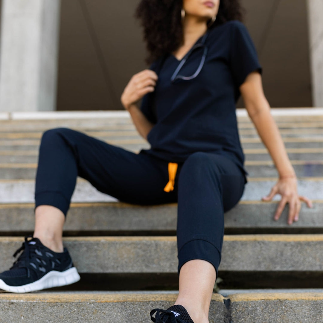 Seated black scrub pants and top.