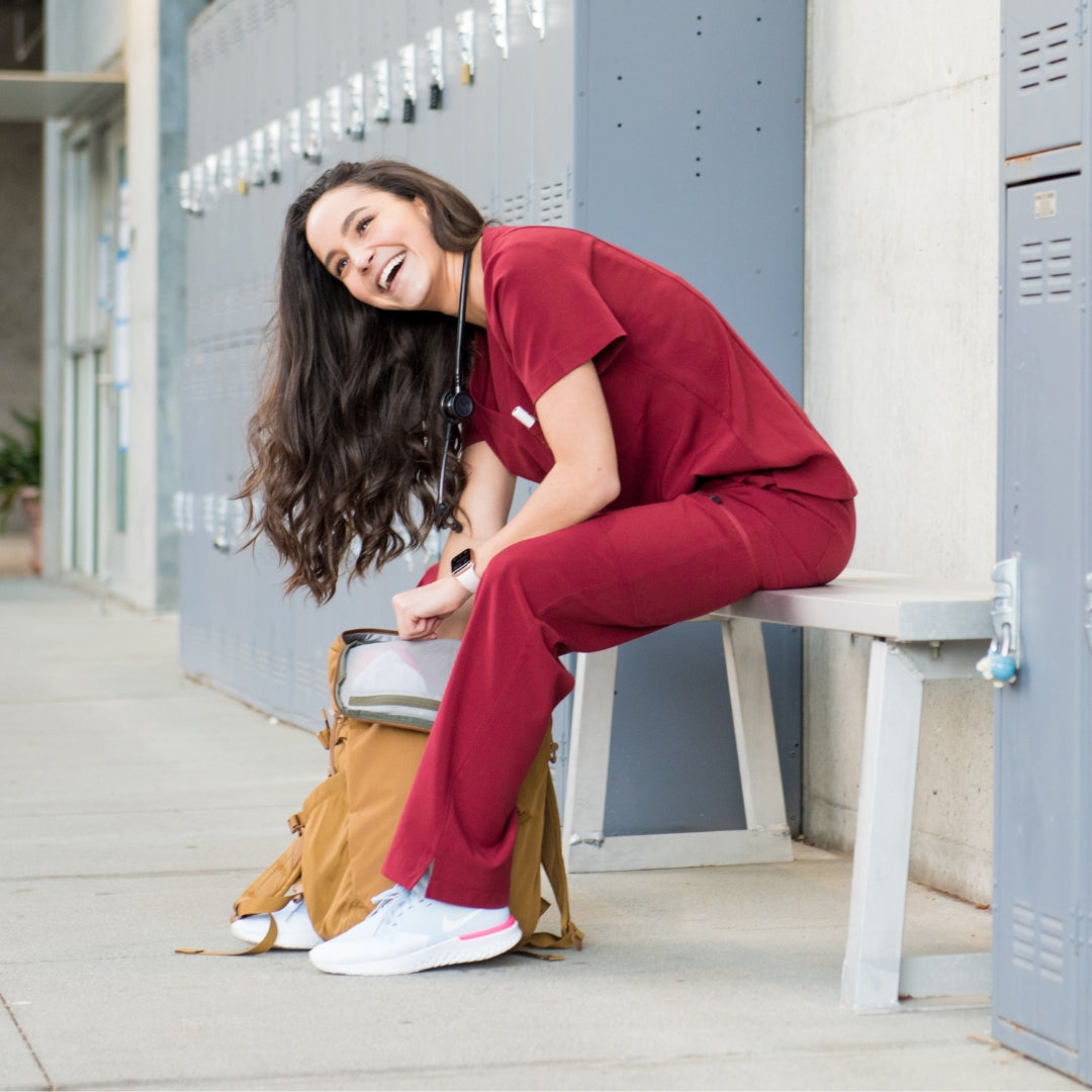 Seated burgundy scrub pants and top.