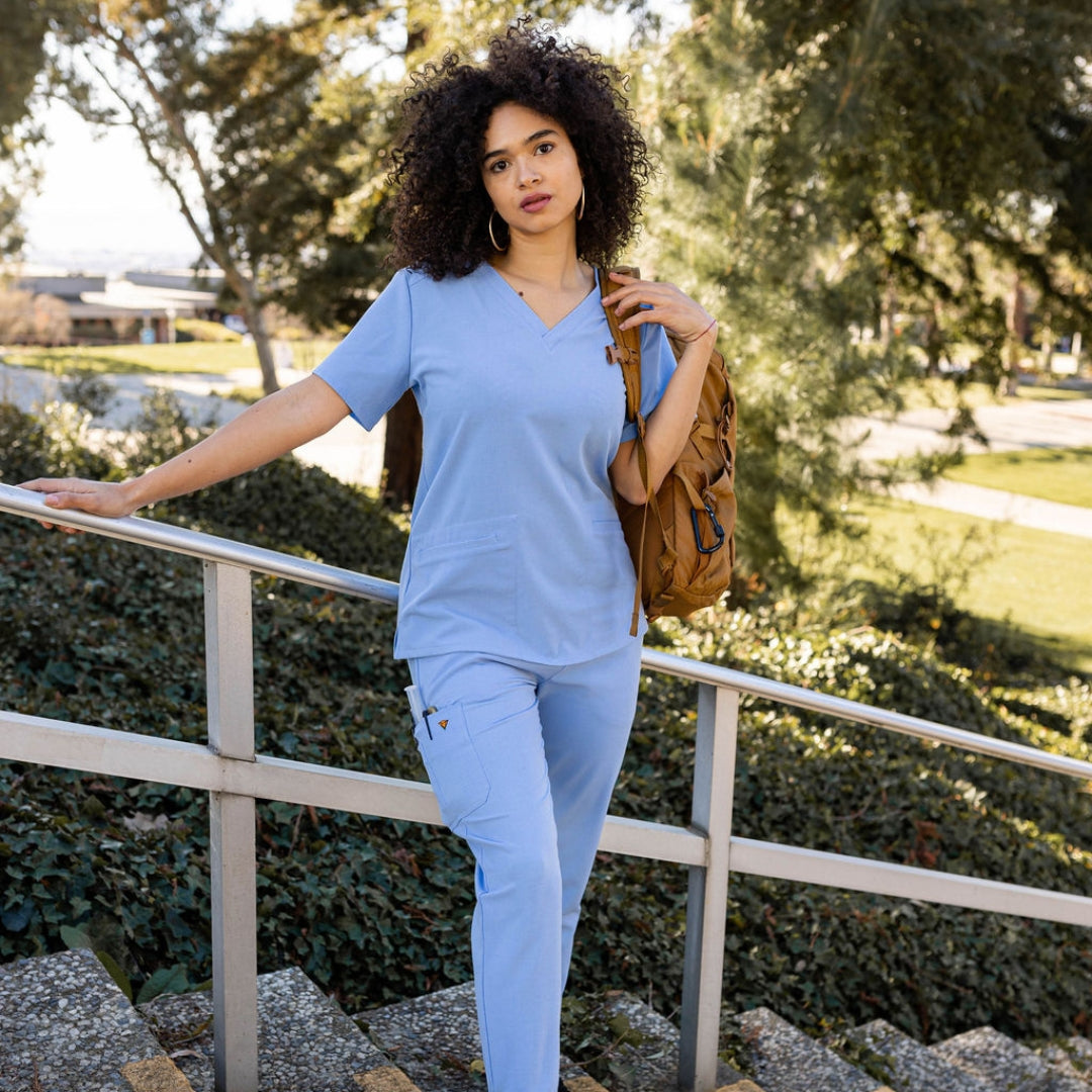 Standing with ceil blue top and scrub bottoms.