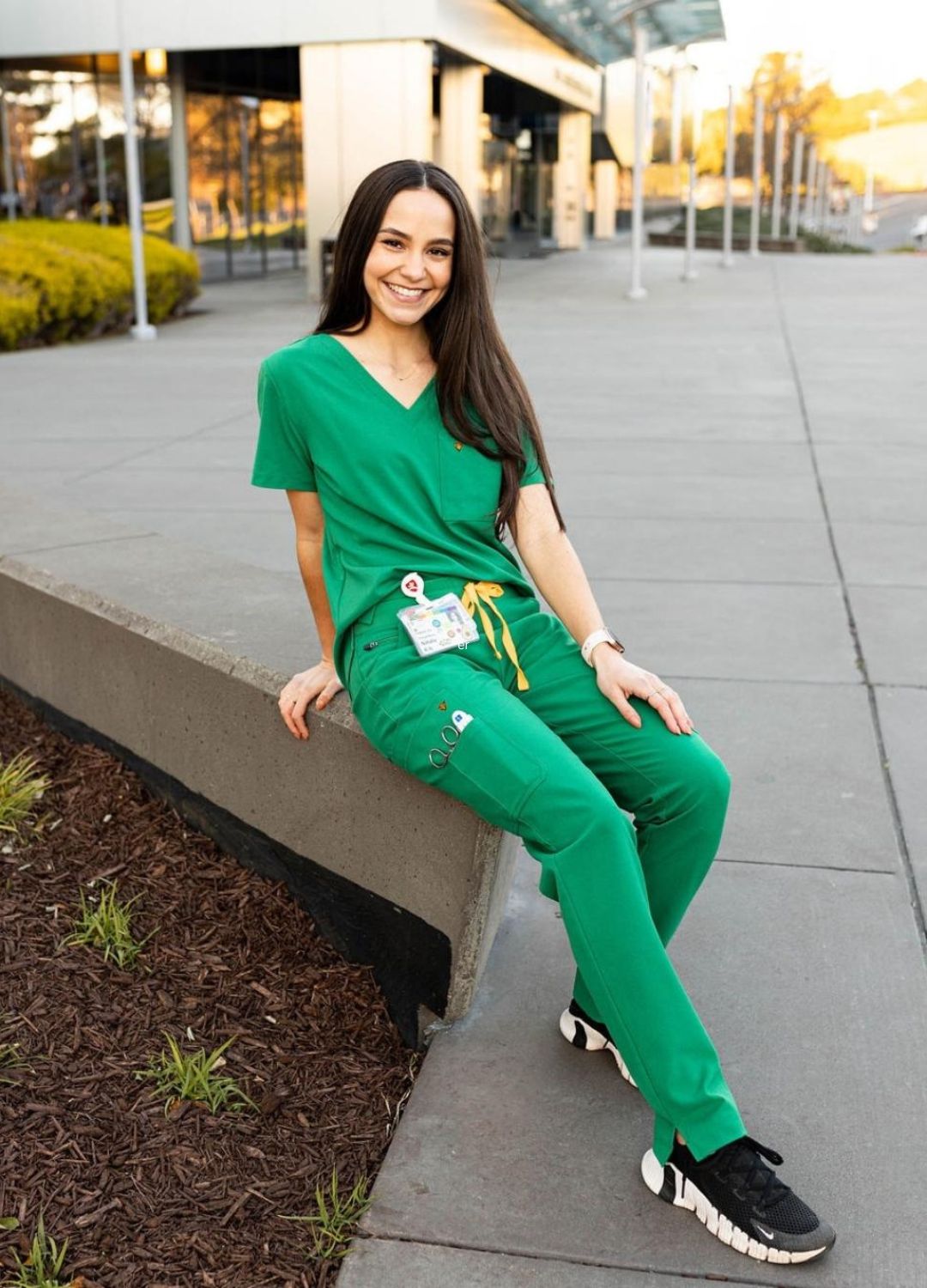 Women's green scrubs seated on bench.