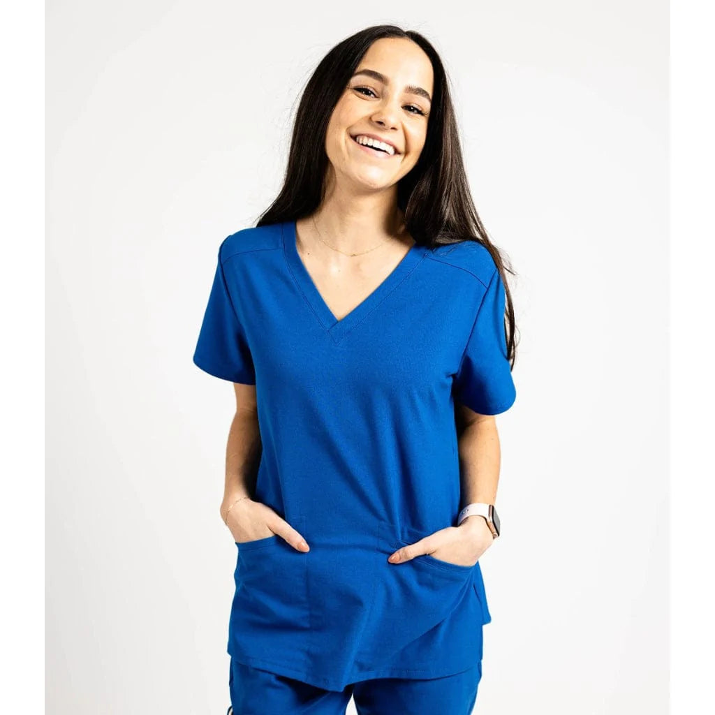 Upper front picture of the the Caswell scrub top in royal blue with hands in pockets.