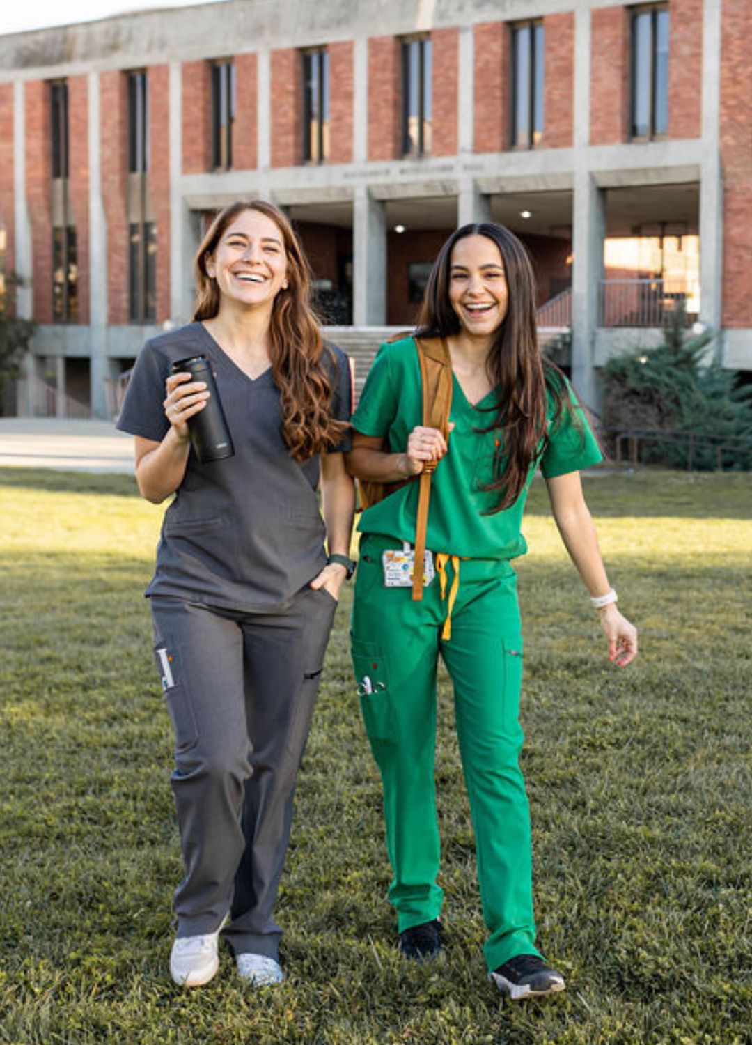 Women's emerald green scrubs walking with friend on grass.