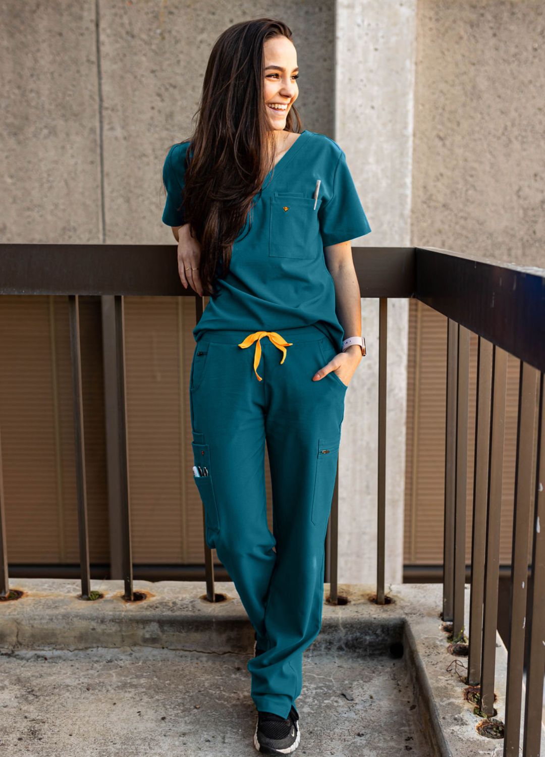 Women's teal scrubs standing outside.