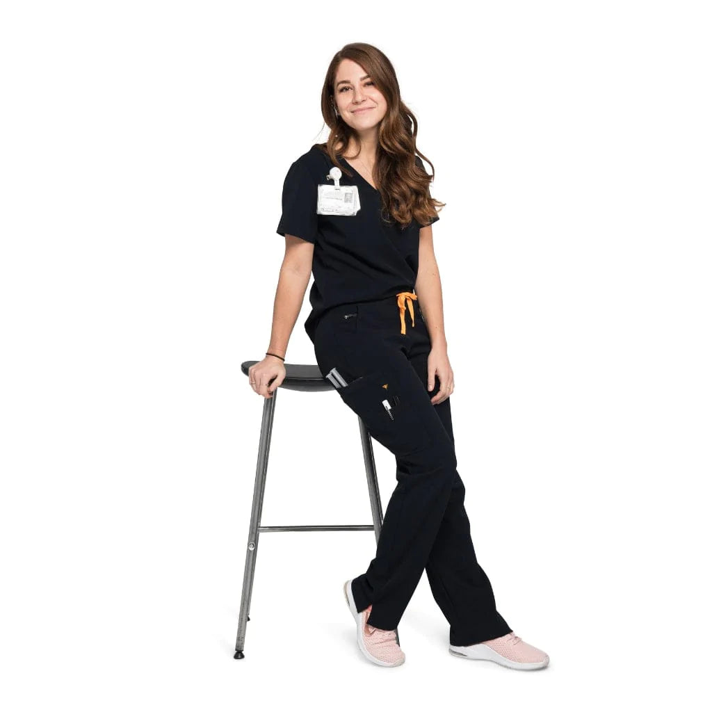 Leaning full body picture of the the Bodie scrub pants in black.