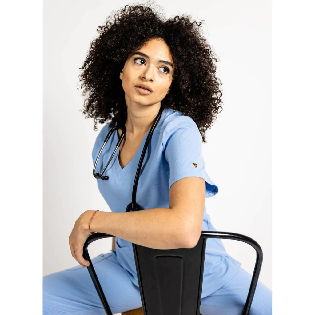 Seated picture of the the Caswell scrub top in ceil blue.