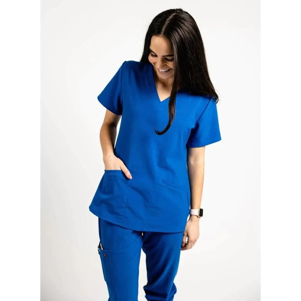 Upper front picture of the the Caswell scrub top in royal blue with one hand in pocket.