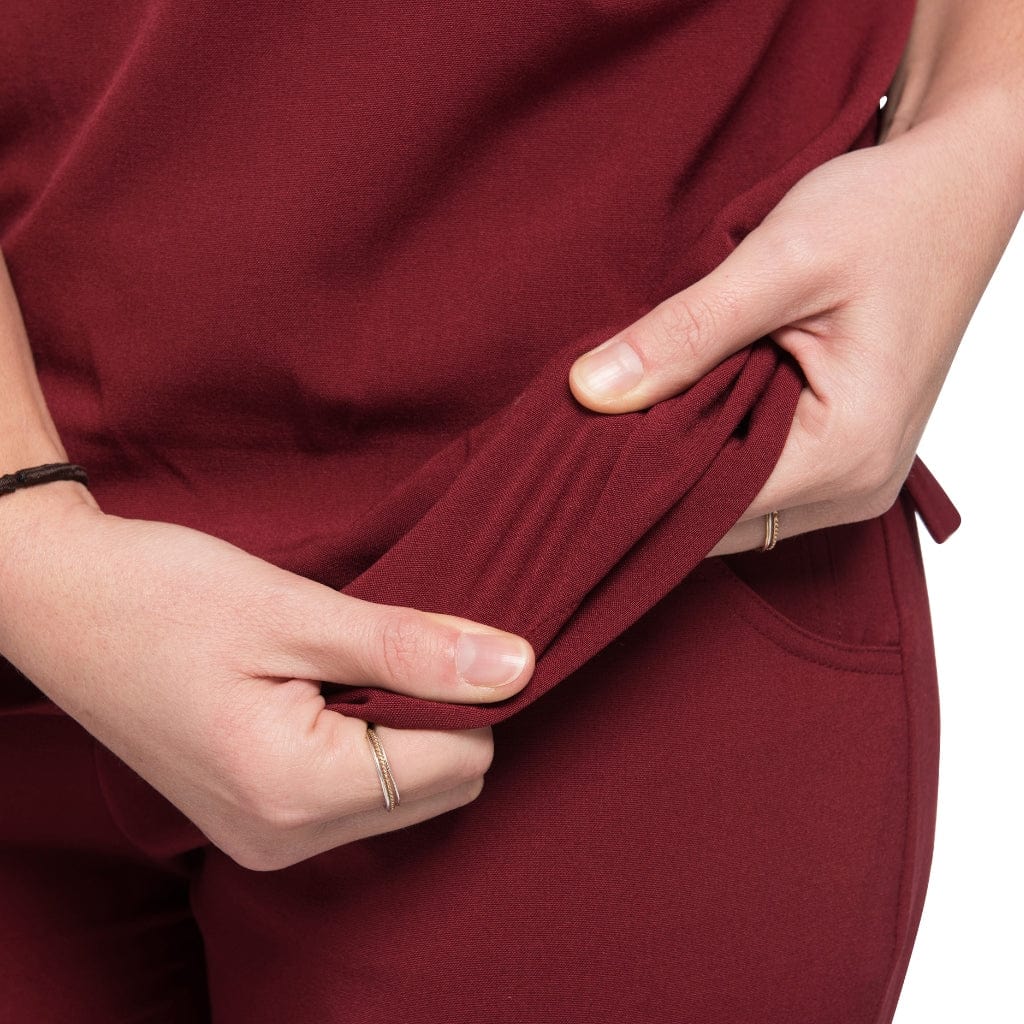 Close up picture of fabric stretch of the wilder one-pocket scrub top in burgundy.