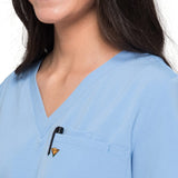 Close up picture of the pocket detail of the wilder one-pocket scrub top in ceil blue.