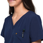 Close up picture of the pocket detail of the wilder one-pocket scrub top in navy blue.