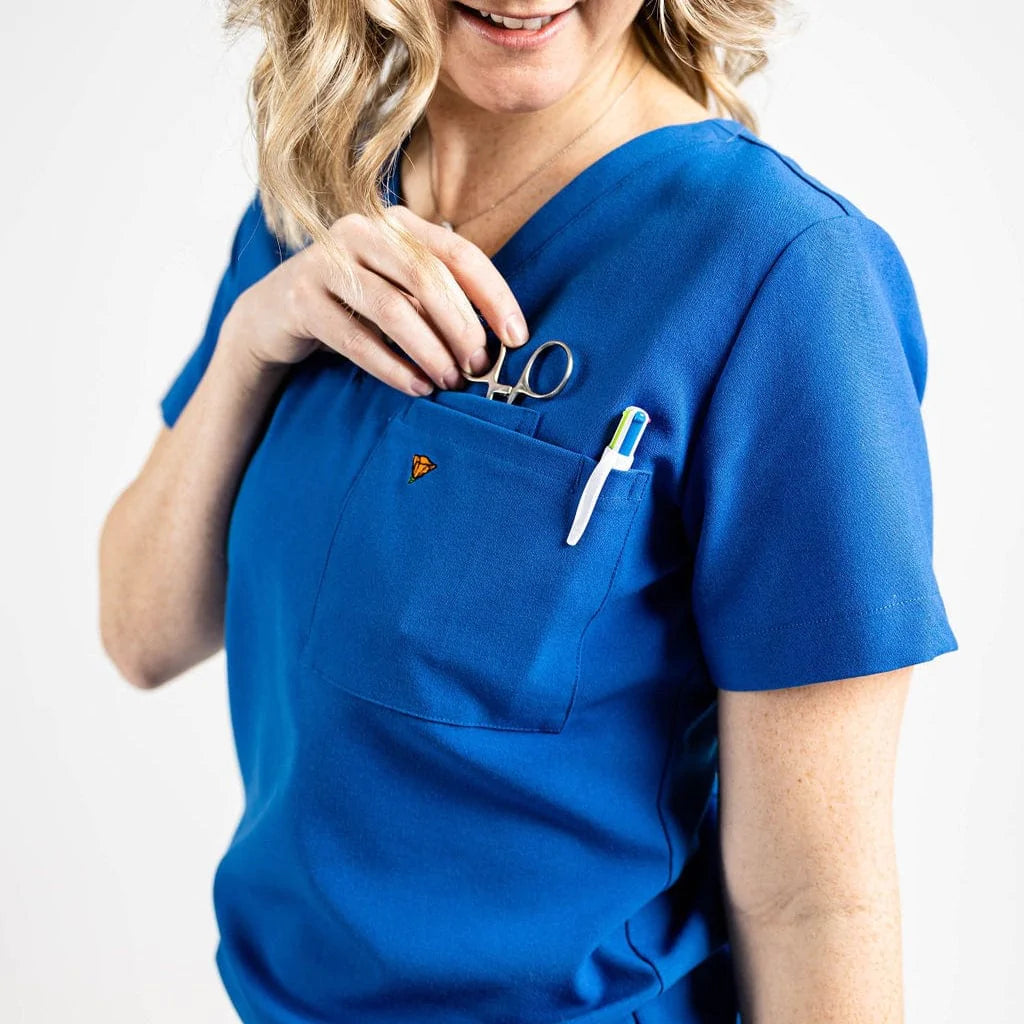 Close up picture of the pocket detail of the wilder one-pocket scrub top in royal blue.